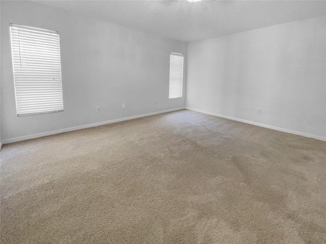 unfurnished room with light carpet and baseboards