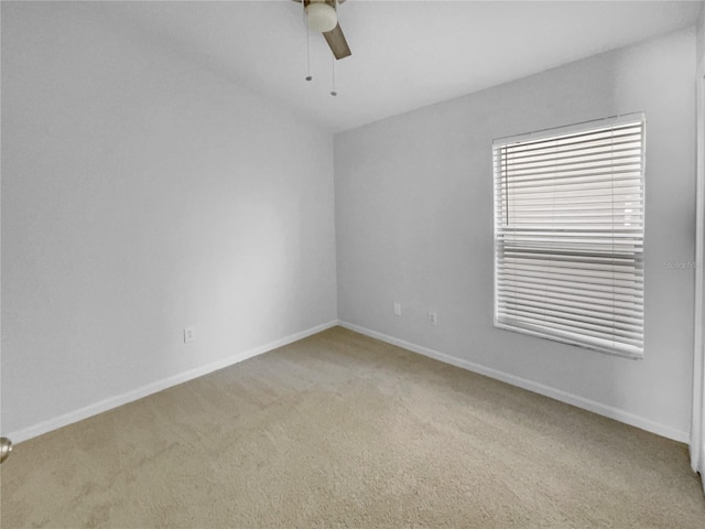 spare room with baseboards, ceiling fan, and light colored carpet