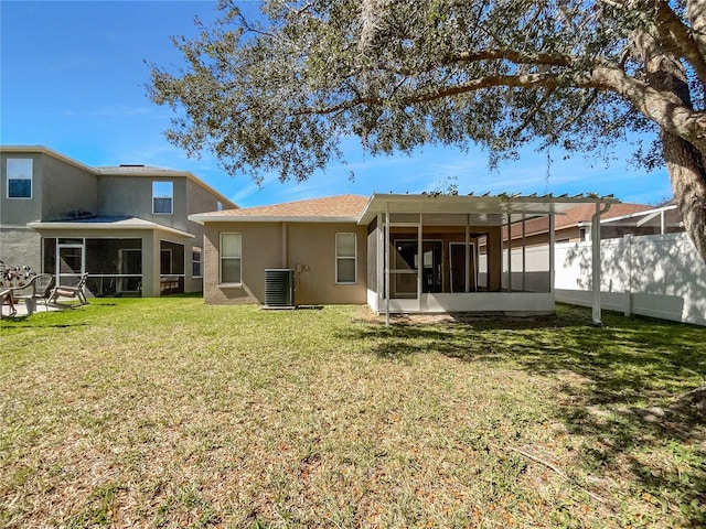 rear view of house featuring central AC unit, a sunroom, fence, a yard, and stucco siding