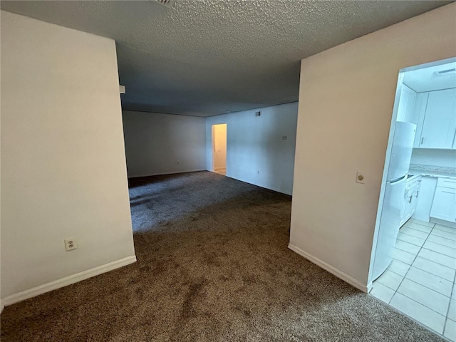 empty room featuring a textured ceiling, baseboards, and light colored carpet