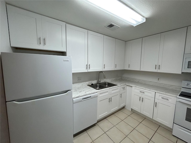 kitchen with white appliances, white cabinets, a sink, and light tile patterned floors