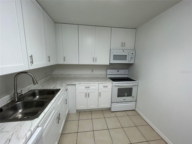 kitchen featuring white appliances, white cabinets, a sink, and light stone countertops