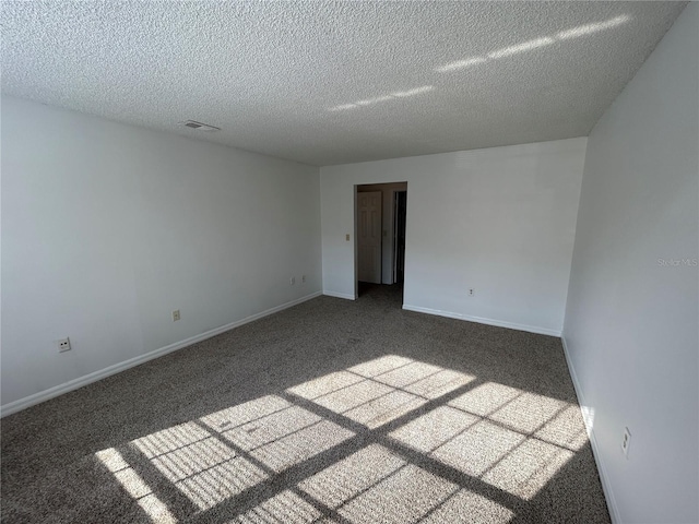 carpeted spare room featuring baseboards, visible vents, and a textured ceiling