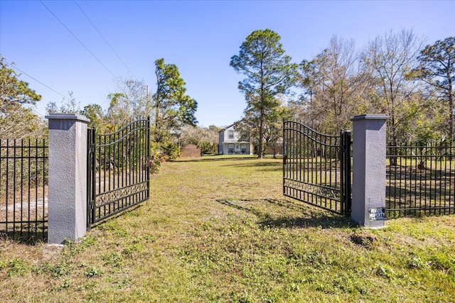 view of gate with fence and a lawn