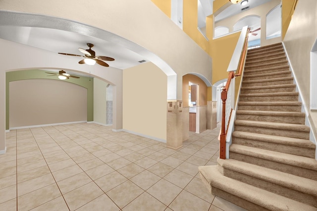 entryway with light tile patterned floors, visible vents, arched walkways, a ceiling fan, and stairway