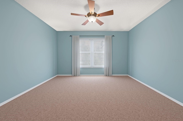 carpeted empty room with a textured ceiling, a ceiling fan, and baseboards