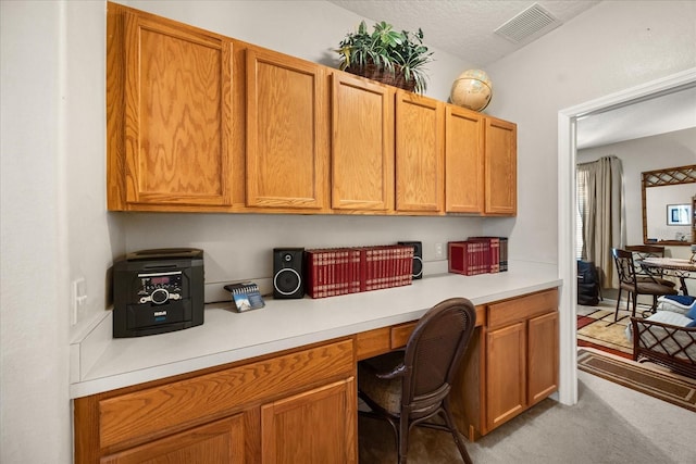 home office with light carpet, built in study area, visible vents, and a textured ceiling