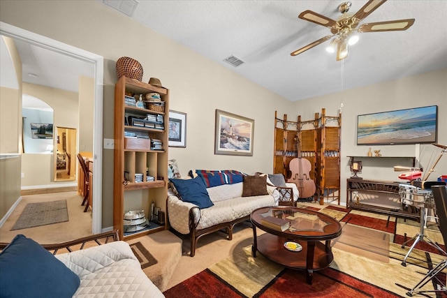 carpeted living room featuring arched walkways, visible vents, a ceiling fan, a textured ceiling, and baseboards