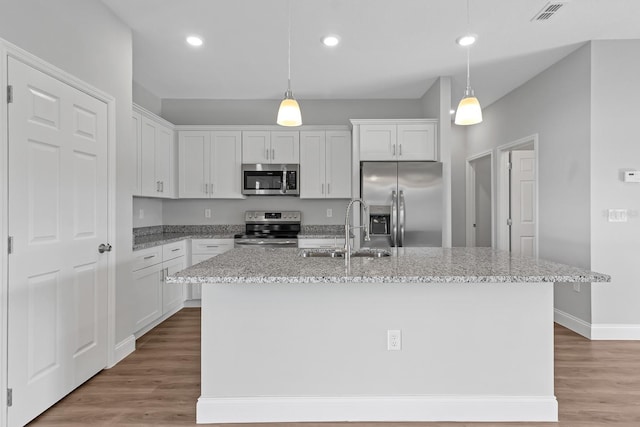 kitchen featuring stainless steel appliances, visible vents, white cabinets, a kitchen island with sink, and a sink