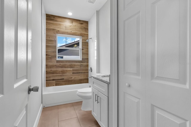 bathroom featuring toilet, tile patterned flooring, vanity, wood walls, and washtub / shower combination