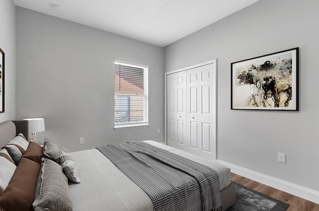 bedroom with a closet, dark wood-style flooring, and baseboards