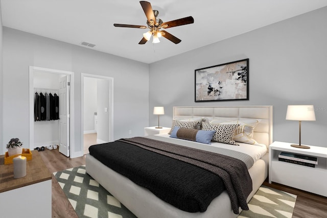 bedroom with wood finished floors, visible vents, baseboards, a ceiling fan, and a closet