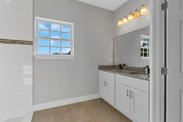 bathroom featuring a wealth of natural light, a sink, baseboards, and double vanity