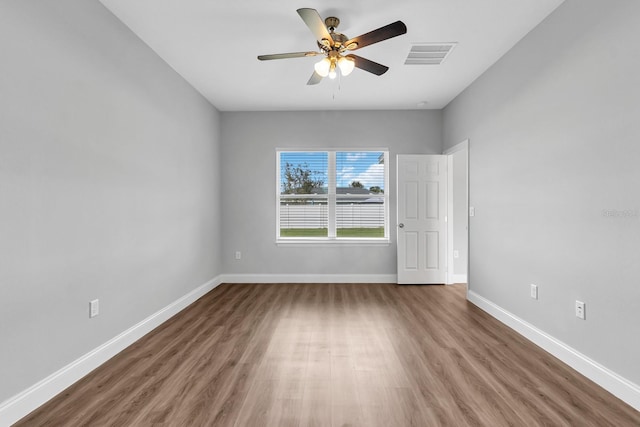 unfurnished room featuring a ceiling fan, baseboards, visible vents, and wood finished floors