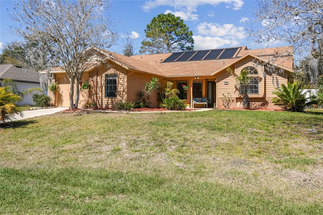 single story home featuring driveway, roof mounted solar panels, an attached garage, a front yard, and brick siding