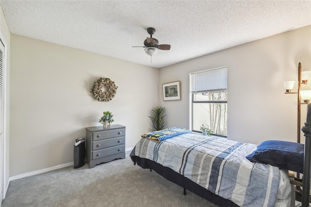 carpeted bedroom with a closet, a textured ceiling, baseboards, and a ceiling fan