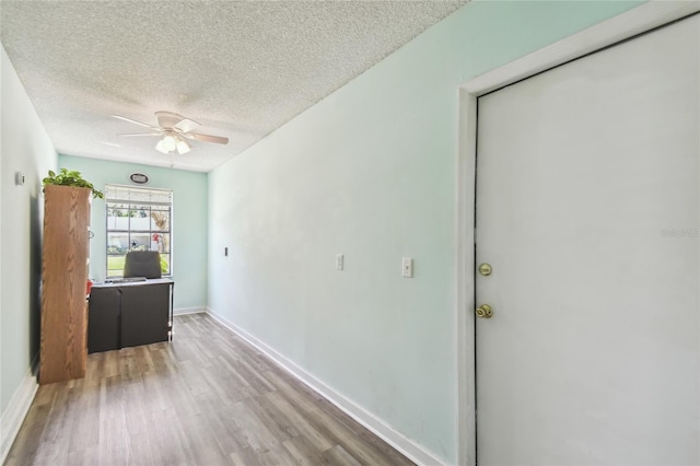 unfurnished room with a ceiling fan, wood finished floors, baseboards, and a textured ceiling