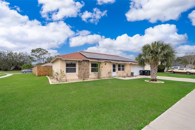 ranch-style house featuring stucco siding, concrete driveway, roof mounted solar panels, a garage, and a front lawn