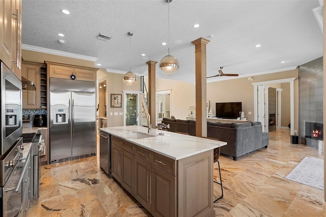 5524 Sail Ct, Orlando, FL 32819 - kitchen with stainless steel appliances, crown molding, decorative columns, a center island with sink, and a sink