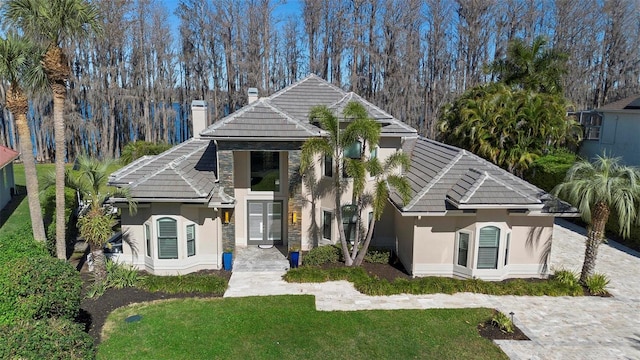 5524 Sail Ct, Orlando, FL 32819 - view of front of home with stucco siding, a tile roof, a chimney, and a front lawn
