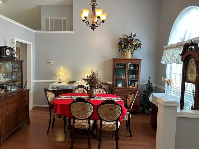 dining space with visible vents, an inviting chandelier, and wood finished floors