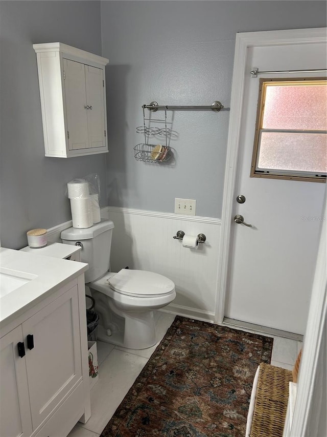 bathroom with vanity, toilet, and wainscoting