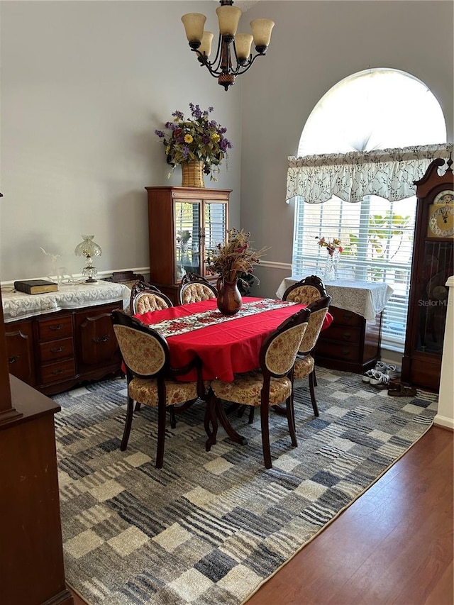 dining space with a high ceiling, a chandelier, and dark wood-style flooring