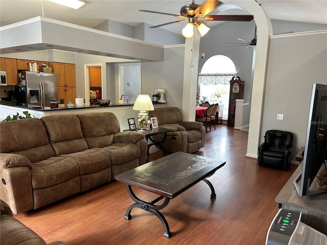 living room with ceiling fan, wood finished floors, crown molding, and vaulted ceiling