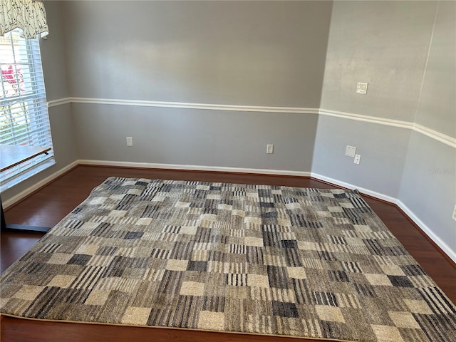 spare room featuring baseboards and wood finished floors