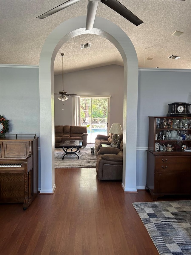 hallway with visible vents, wood finished floors, arched walkways, and lofted ceiling