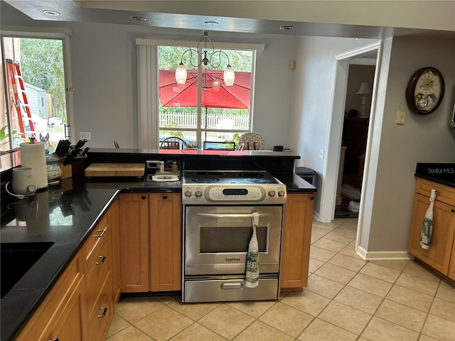 kitchen with dark countertops, plenty of natural light, stainless steel range with electric cooktop, and light tile patterned floors