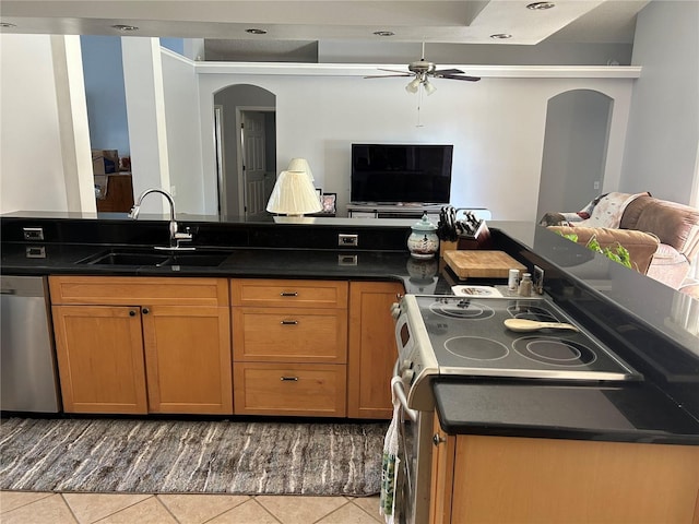 kitchen featuring arched walkways, open floor plan, stainless steel appliances, and a sink