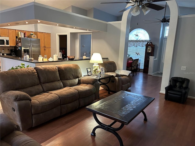 living room with dark wood finished floors, a ceiling fan, arched walkways, and baseboards