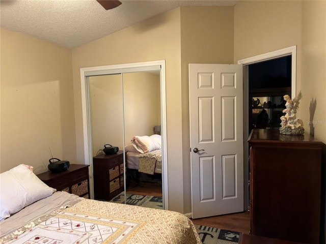 bedroom with a ceiling fan, a textured ceiling, wood finished floors, a closet, and vaulted ceiling