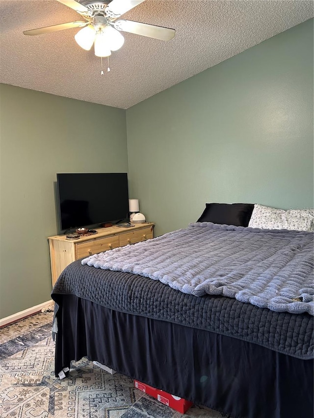 bedroom featuring baseboards, a textured ceiling, and a ceiling fan