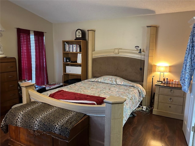 bedroom with dark wood-type flooring, lofted ceiling, and a textured ceiling