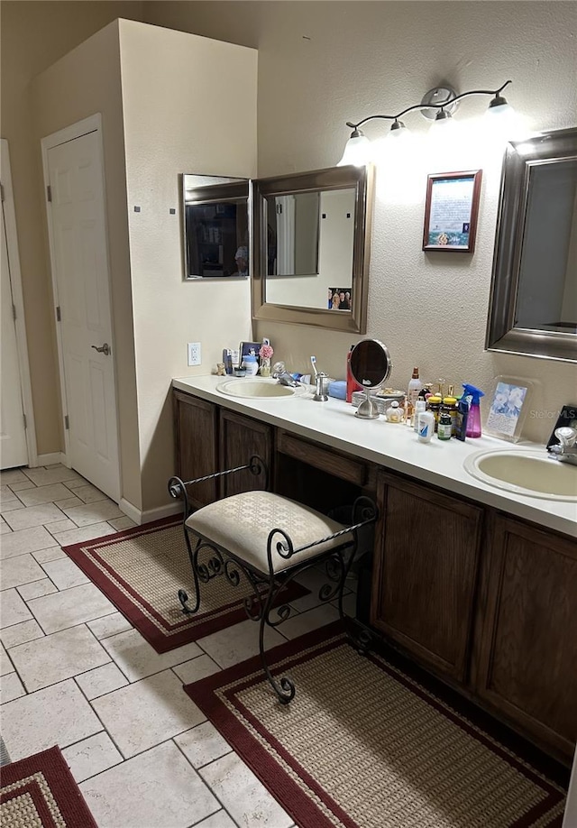 bathroom with double vanity, baseboards, and a sink