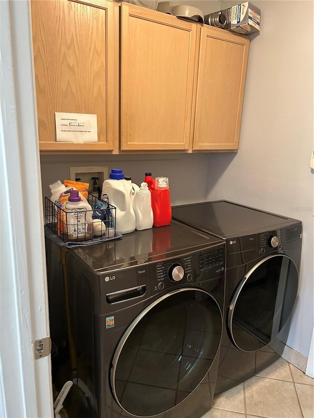 laundry area featuring tile patterned floors, cabinet space, and washing machine and clothes dryer