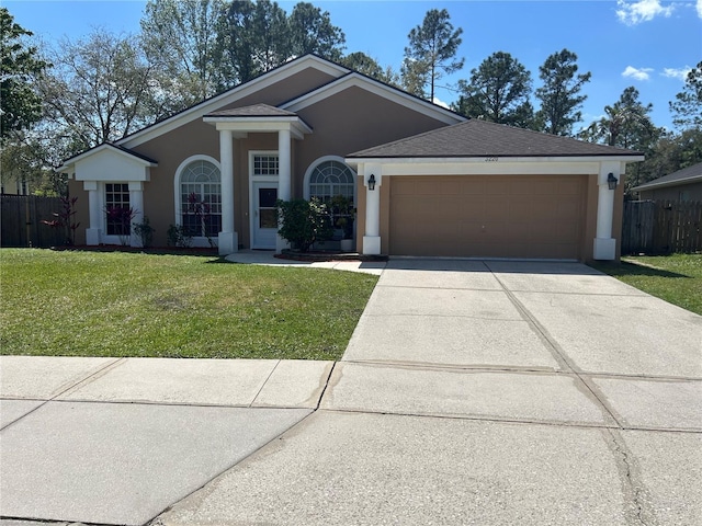 view of front facade with fence, a front yard, stucco siding, a garage, and driveway