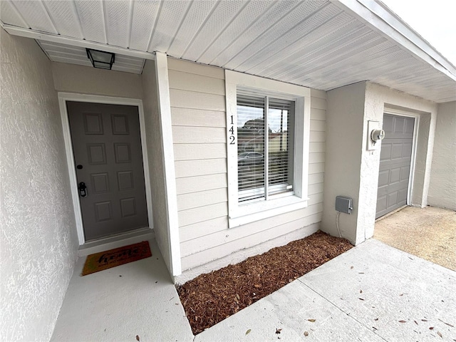 property entrance with a garage and stucco siding