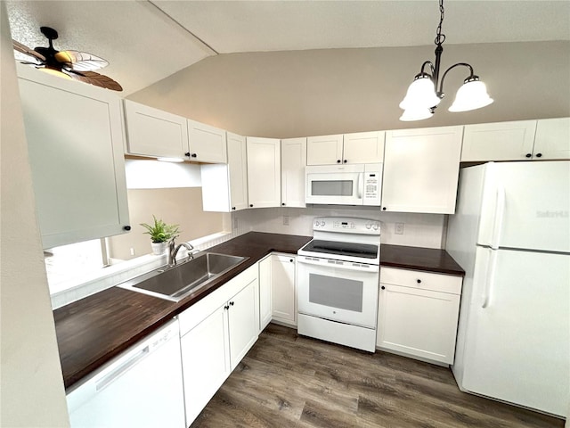 kitchen with white appliances, dark countertops, a sink, and white cabinets