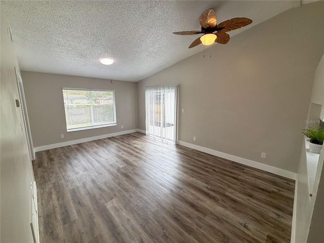 spare room featuring dark wood-style floors, a textured ceiling, vaulted ceiling, and baseboards