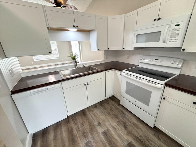 kitchen with white appliances, a sink, white cabinetry, dark wood-style floors, and dark countertops