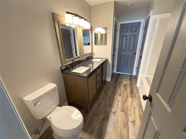 bathroom featuring double vanity, wood finished floors, a sink, and visible vents