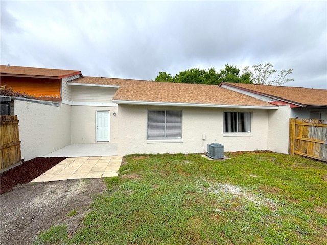 rear view of property with a yard, a patio, stucco siding, a shingled roof, and fence