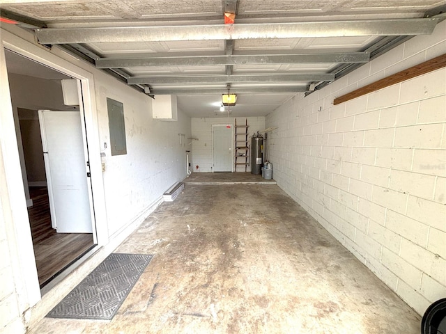 garage featuring concrete block wall, a garage door opener, freestanding refrigerator, electric water heater, and electric panel