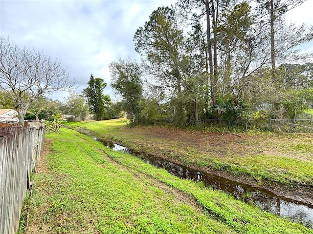 view of yard featuring a water view and fence