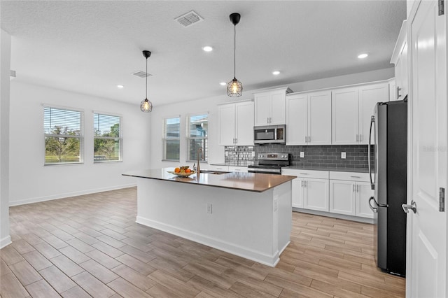 kitchen with visible vents, decorative backsplash, appliances with stainless steel finishes, white cabinetry, and a sink