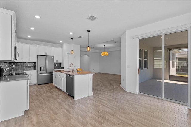 kitchen featuring visible vents, backsplash, appliances with stainless steel finishes, arched walkways, and a sink