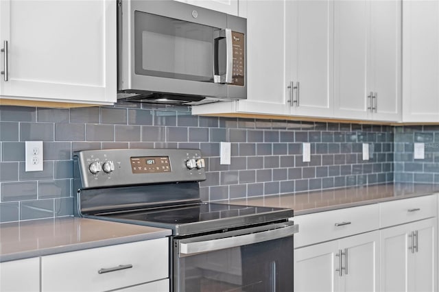 kitchen featuring decorative backsplash, white cabinets, and appliances with stainless steel finishes